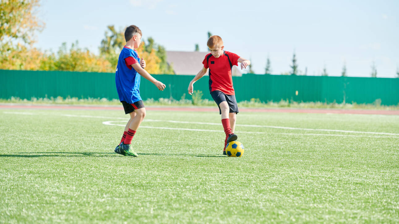 niños jugando al futbol en campo de futbol