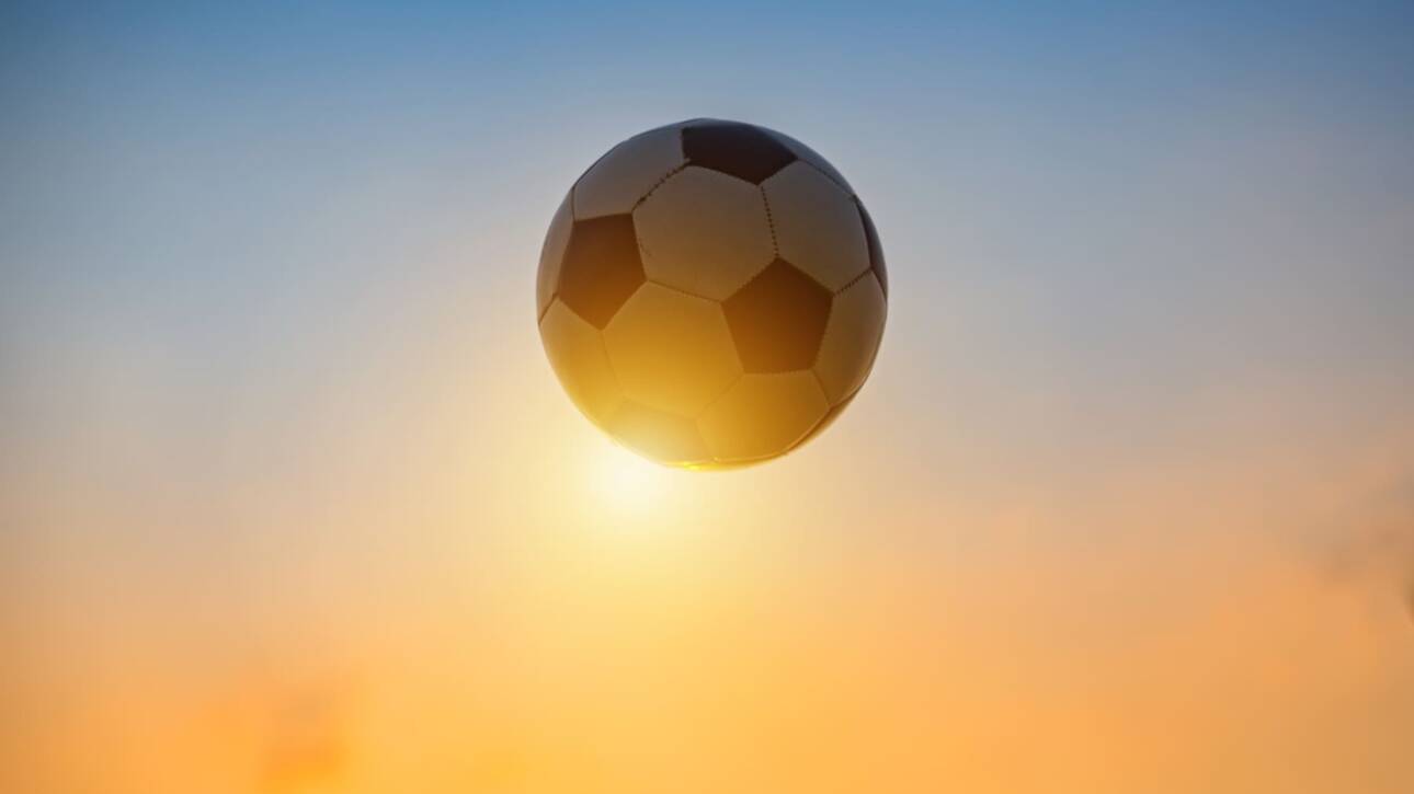 balon de futbol frente al sol del atardecer