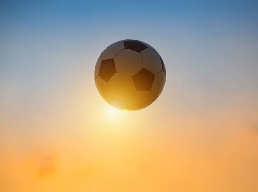 balon de futbol frente al sol del atardecer