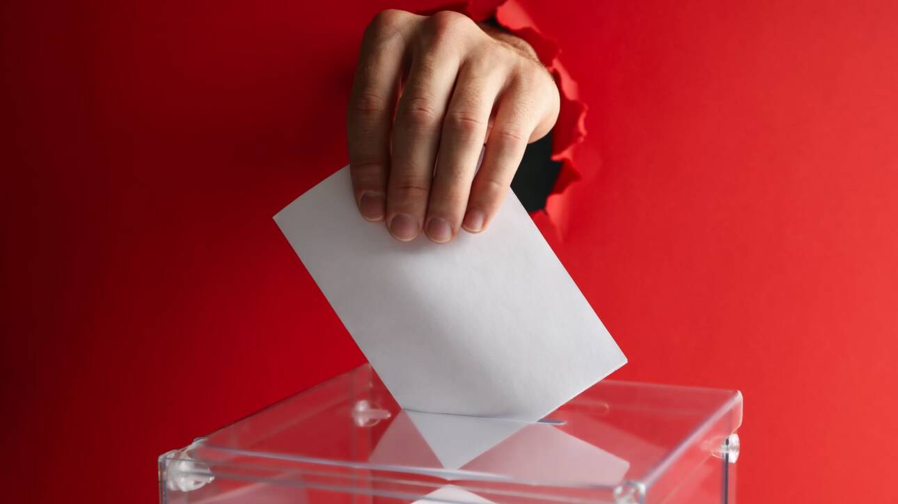 mano metiendo voto en urna con fondo rojo